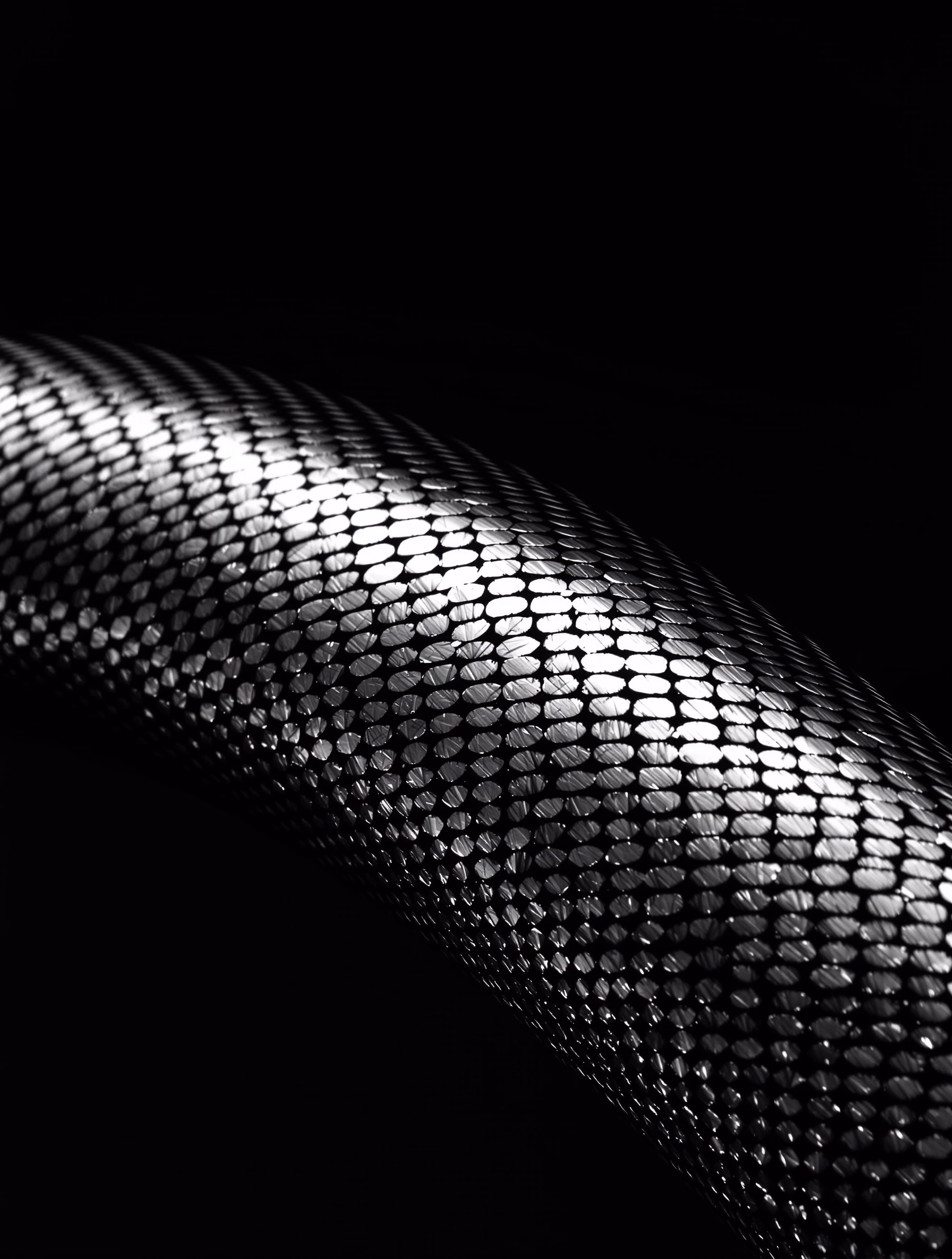 A curved titanium surface, structural in its repeating pattern.