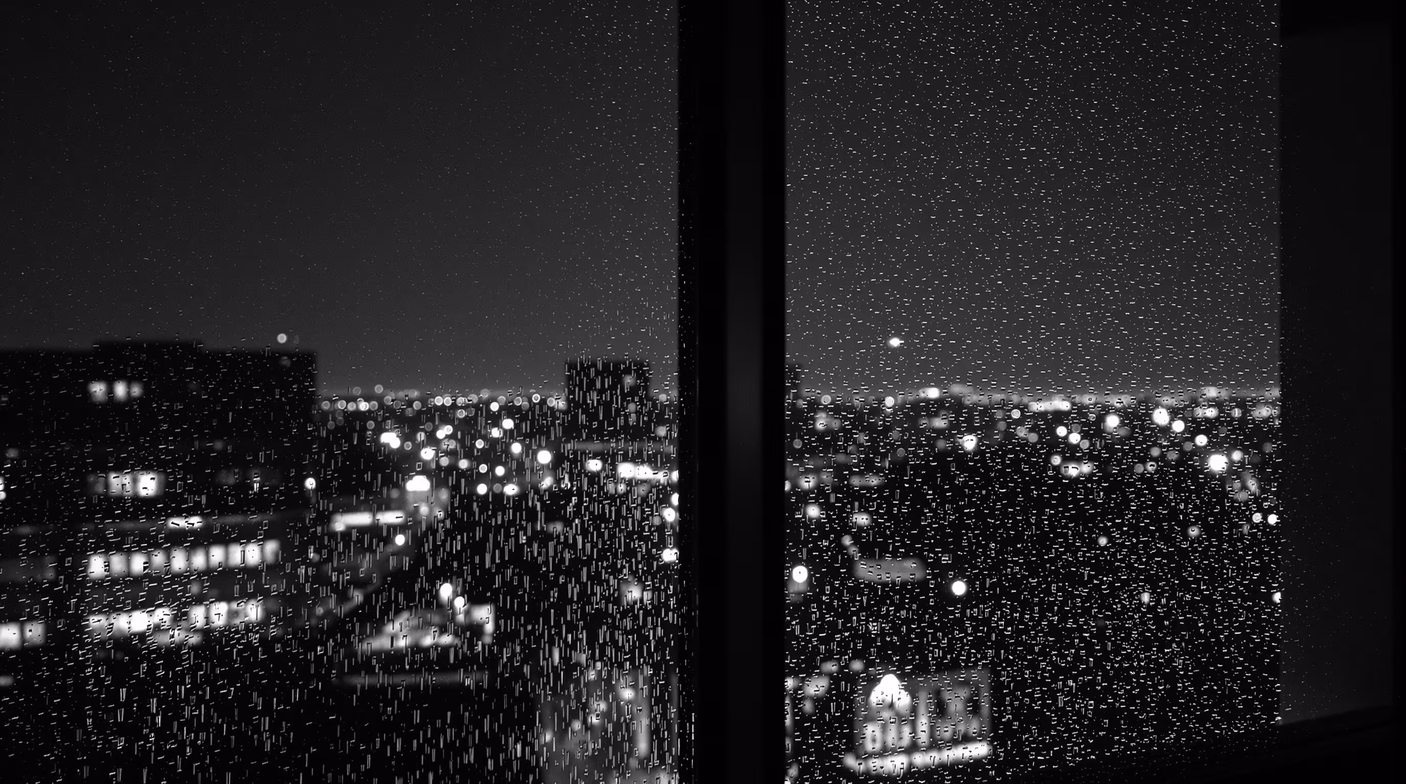 A London EC3 office window at night, rain on the glass and city lights blurred beyond.